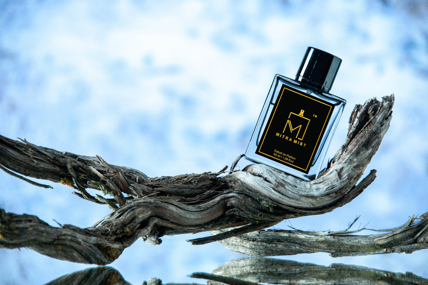 Mitra Mist perfume bottle on a branch against a blue sky